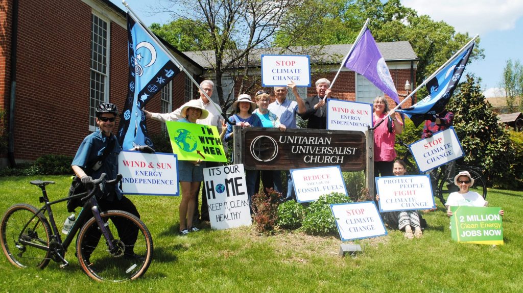 People gathered around UUCR sign holding signs for climate change