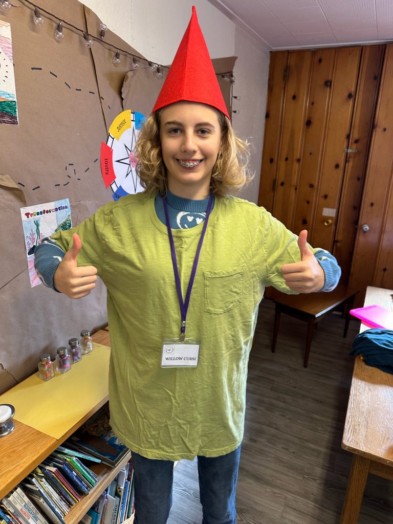 Kid dressed up as an elf with a red pointy hat and a green shirt