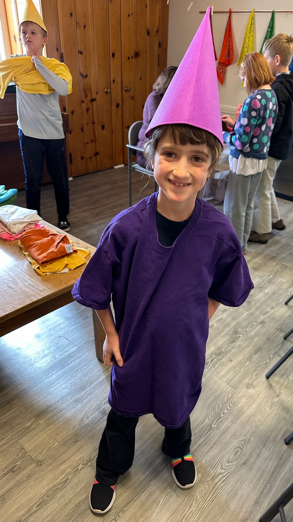 Child dressed up as an elf with a pink hat and purple shirt